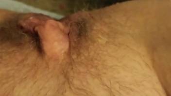 Close-up scene of a woman rubbing her hairy pussy